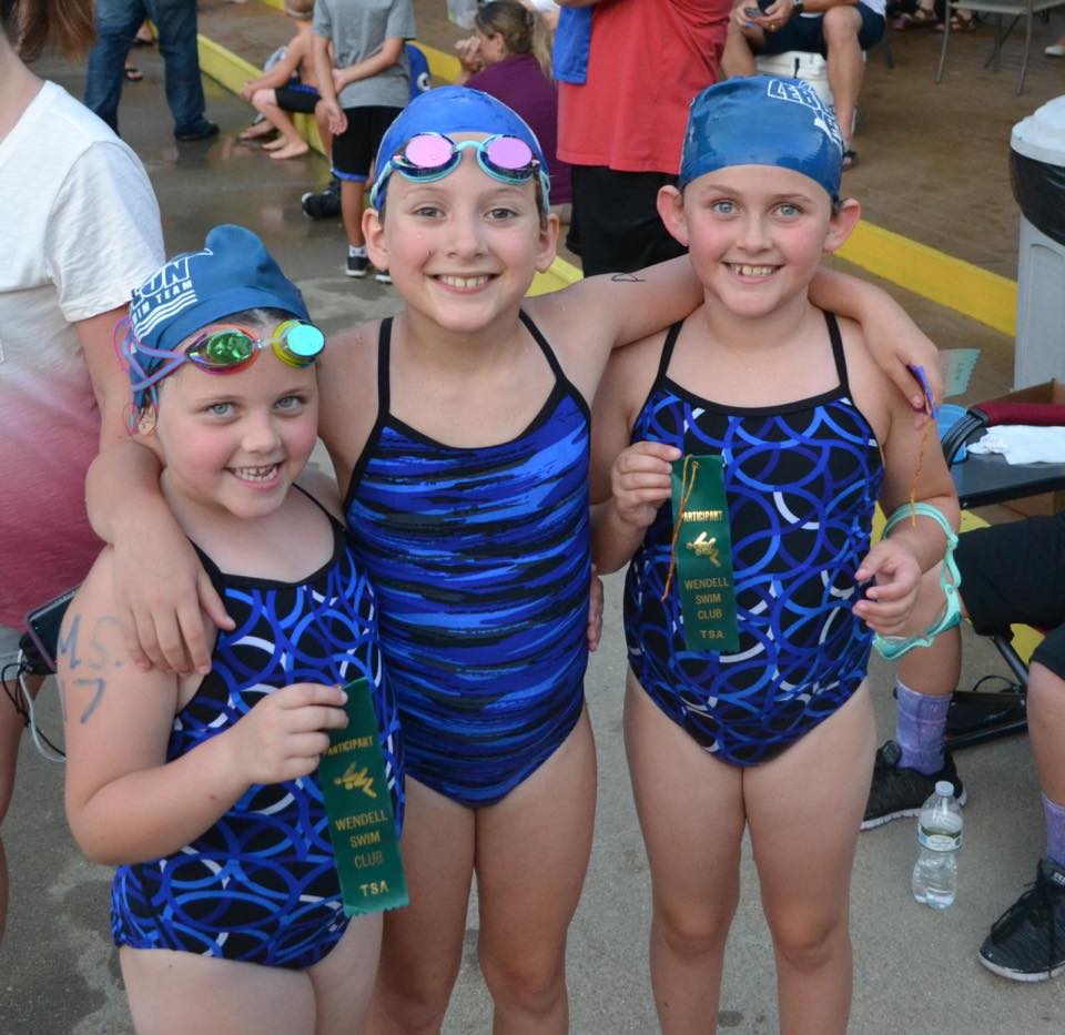 three happy swimmers at a meet
